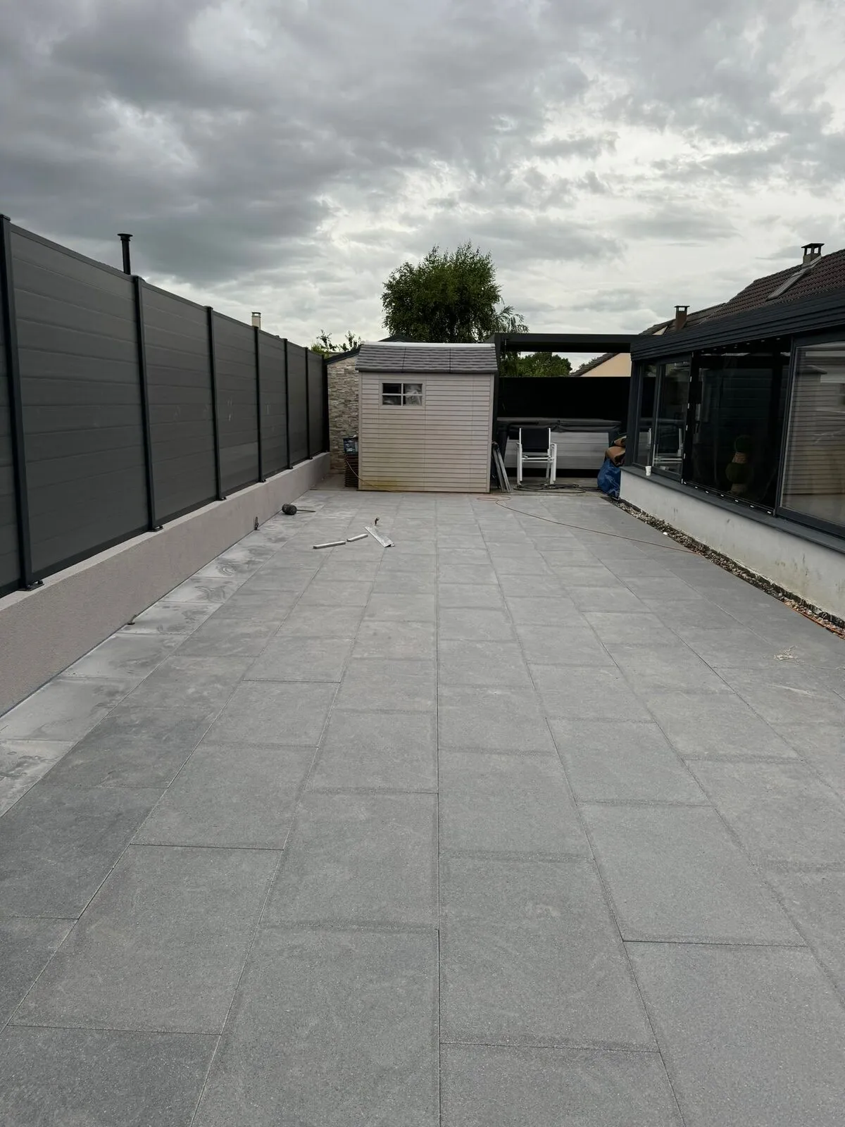 Grande terrasse en dalles grises le long d'une clôture composite, posée près de Metz